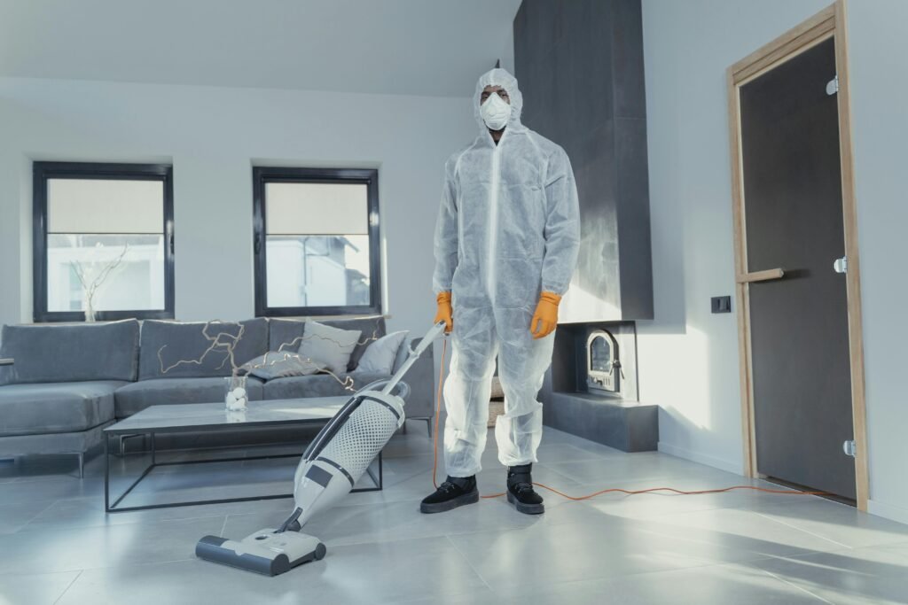 A person in protective coveralls vacuuming a contemporary living room.